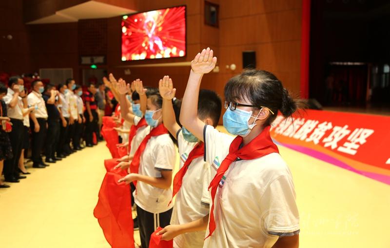 图为少年儿童为参会嘉宾佩戴红领巾